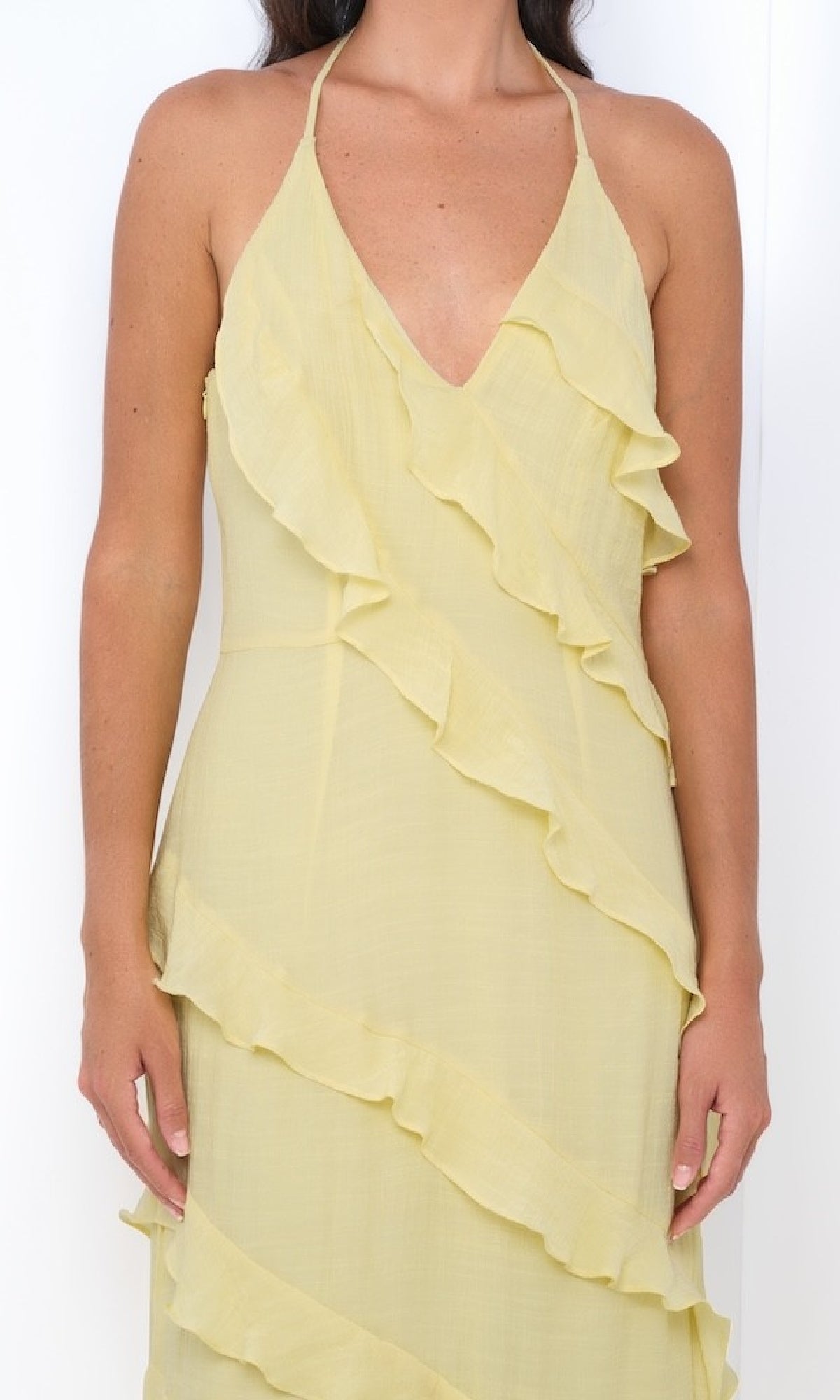 A woman wears the Remi by Velvi V-Neck Halter Ruffled Long Prom Dress in light yellow, standing against a white background.